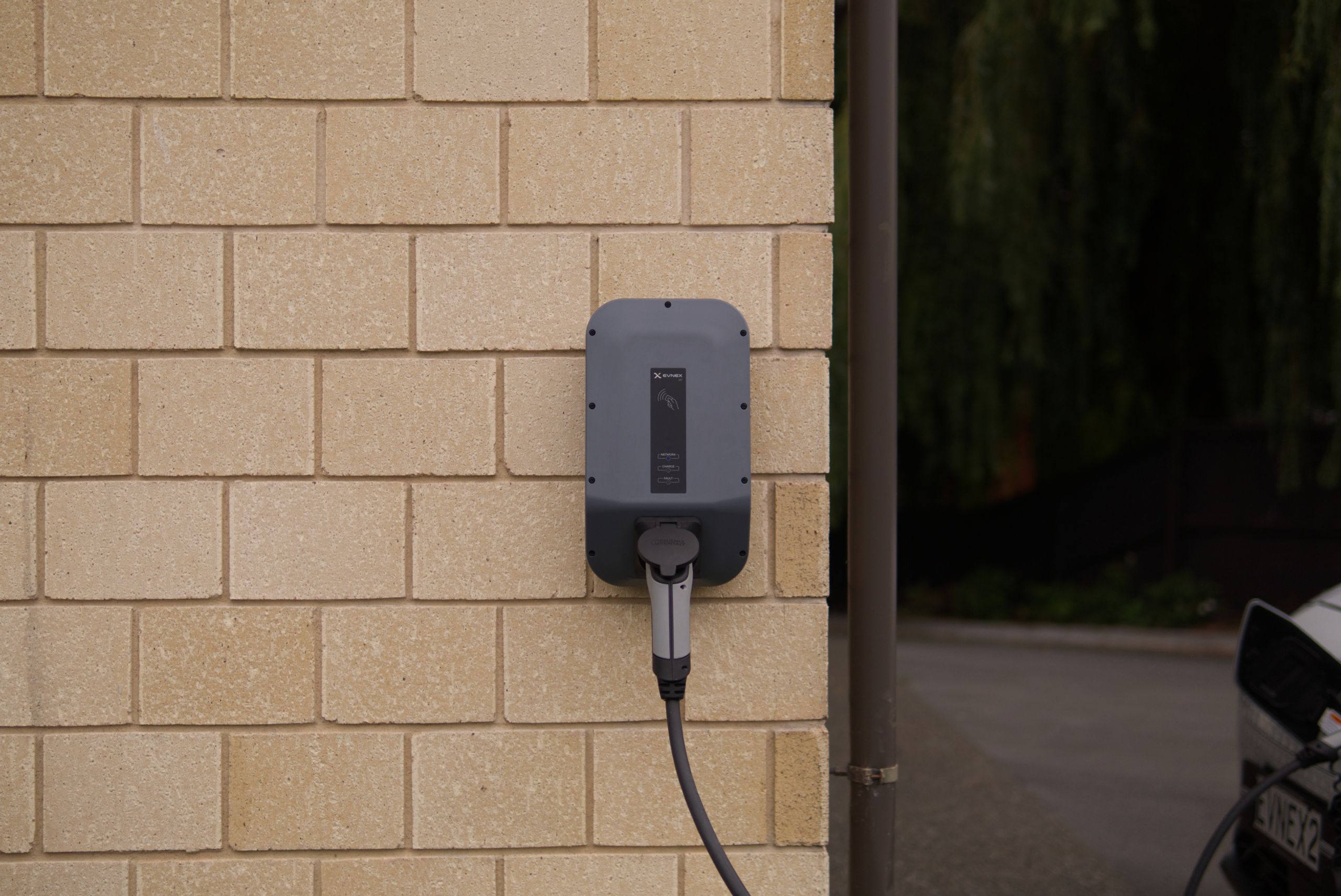 A wall-mounted electric vehicle charging station installed on a brick wall.